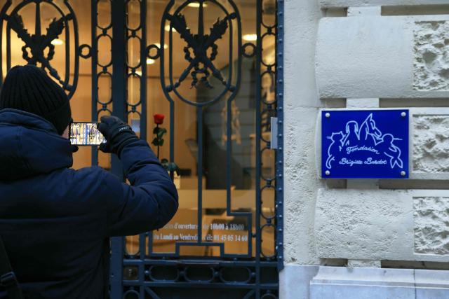A member of the public takes a photo of the entrance of the Fondation Brigitte Bardot with a rose set on the door following the death of French actress and animal rights activist Brigitte Bardot in Paris on December 28, 2025. French film legend Brigitte Bardot died at 91 AFP learnt from the Brigitte Bardot Foundation on December 28, 2025. (Photo by Alain JOCARD / AFP)