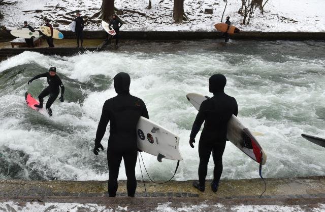 (FILES) A surfer rides an artificial wave in the canal of the Eisbach (ice creek) river at the English Garden park in Munich, southern Germany, on January 16, 2021. A temporary ramp installed in Munich's Eisbach, which had provisionally restored the famous surfing wave, has been removed by the fire brigade on December 28, 2025, according to a spokesperson. The wave had disappeared in October 2025 after cleaning works of the creek bed. (Photo by Christof STACHE / AFP)