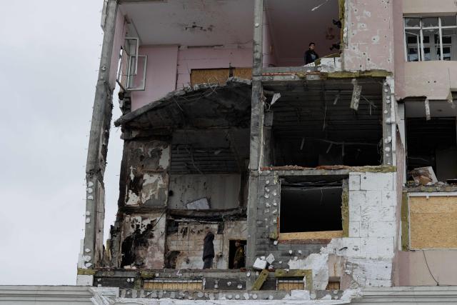 People stand inside a damaged residential building following Russian drones and missiles attack, in Kyiv, on December 28, 2025, amid the Russian invasion in Ukraine. A Russian drone and missile barrage on Kyiv and its suburbs killed one person, wounded two dozen and cut off heating and electricity for hundreds of thousands of people left in freezing temperatures on December 27, 2025. (Photo by Tetiana DZHAFAROVA / AFP)