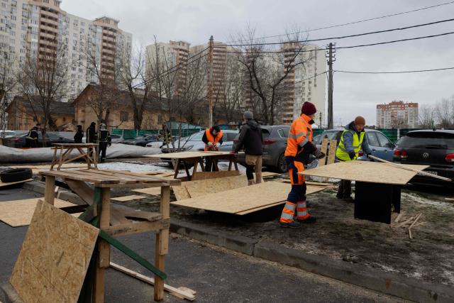 Workers prepare plywood for damaged windows in a damaged residential building following Russian drones and missiles attack, in Kyiv, on December 28, 2025, amid the Russian invasion in Ukraine. A Russian drone and missile barrage on Kyiv and its suburbs killed one person, wounded two dozen and cut off heating and electricity for hundreds of thousands of people left in freezing temperatures on December 27, 2025. (Photo by Tetiana DZHAFAROVA / AFP)