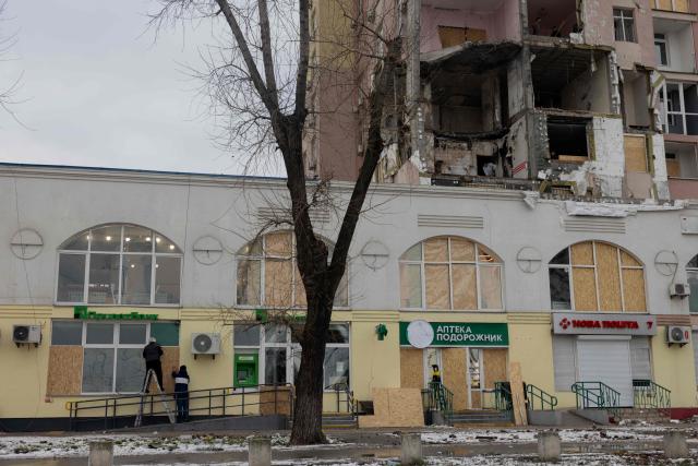 Men cover damaged windows with plywood in a damaged residential building following Russian drones and missiles attack, in Kyiv, on December 28, 2025, amid the Russian invasion in Ukraine. A Russian drone and missile barrage on Kyiv and its suburbs killed one person, wounded two dozen and cut off heating and electricity for hundreds of thousands of people left in freezing temperatures on December 27, 2025. (Photo by Tetiana DZHAFAROVA / AFP)