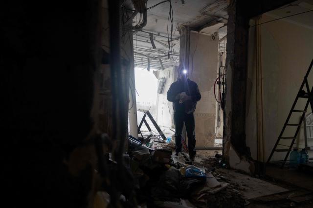 A man with a flashlight stands inside a damaged residential building following Russian drones and missiles attack, in Kyiv, on December 28, 2025, amid the Russian invasion in Ukraine. A Russian drone and missile barrage on Kyiv and its suburbs killed one person, wounded two dozen and cut off heating and electricity for hundreds of thousands of people left in freezing temperatures on December 27, 2025. (Photo by Tetiana DZHAFAROVA / AFP)