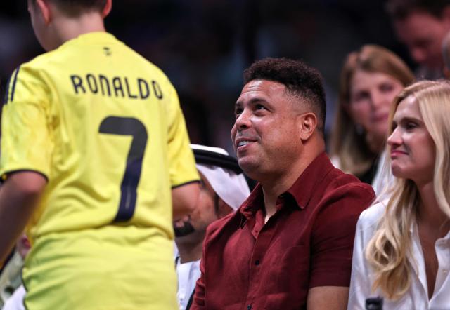Brazilian former footballer player Ronaldo (C) and partner, model Celina Locks, look on courtside as they watch the Battle of the Sexes exhibition tennis match between Belarus’ Aryna Sabalenka and Australia's Nick Kyrgios in Dubai on December 28, 2025. (Photo by Christopher Pike / POOL / AFP)