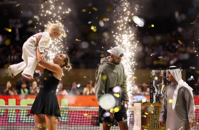 Belarus' Aryna Sabalenka (L) celebrates with her goddaughter Nicole as Australia's Nick Kyrgios looks on at the end of their Battle of the Sexes exhibition tennis match in Dubai on December 28, 2025. Kyrgios won the match. (Photo by Amr Alfiky / POOL / AFP)