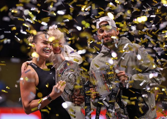 Belarus' Aryna Sabalenka (L), her goddaughter Nicole, and Australia's Nick Kyrgios celebrate with trophies at the end of the Battle of the Sexes exhibition tennis match in Dubai on December 28, 2025. (Photo by Amr Alfiky / POOL / AFP)
