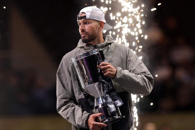 Australia's Nick Kyrgios holds his trophy after winning his Battle of the Sexes exhibition tennis match against Belarus' Aryna Sabalenka in Dubai on December 28, 2025. (Photo by Christopher Pike / POOL / AFP)