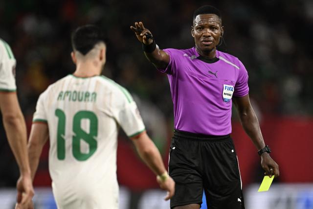 Ghanaian referee Daniel Nii Ayi Laryea (R) gives a yellow card to Algeria's forward #18 Mohamed Amoura (L) during the Africa Cup of Nations (CAN) Group E football match between Algeria and Burkino Faso at Moulay Hassan Stadium in Rabat on December 28, 2025. (Photo by Paul ELLIS / AFP)
