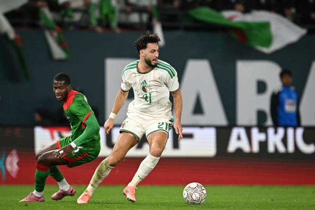 Algeria's defender #21 Ramy Bensebaini (C) fights for the ball with Burkina Faso's forward #07 Dango Ouattara (L) during the Africa Cup of Nations (CAN) Group E football match between Algeria and Burkino Faso at Moulay Hassan Stadium in Rabat on December 28, 2025. (Photo by Paul ELLIS / AFP)