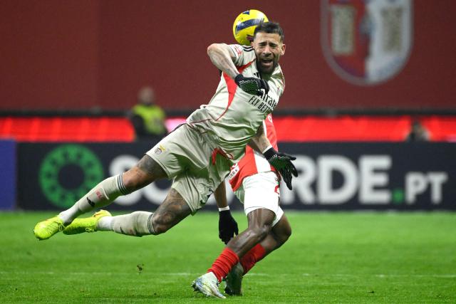 SL Benfica's Argentine defender #30 Nicolas Otamendi (L) fights for the ball with Sporting Braga's Ivorian midfielder #20 Mario Dorgeles during the Portuguese League football match between SC Braga and SL Benfica at Municipal Stadium in Braga on December 28, 2025. (Photo by Miguel RIOPA / AFP)