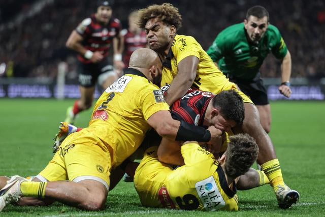 Toulouse's French hooker Julien Marchand (C) is tackled as he dives to score a try during the French Top14 rugby union match between Stade Toulousain Rugby (Toulouse) and Stade Rochelais (La Rochelle) at the Ernest-Wallon stadium in Toulouse, south-western France on December 28, 2025. (Photo by Valentine CHAPUIS / AFP)