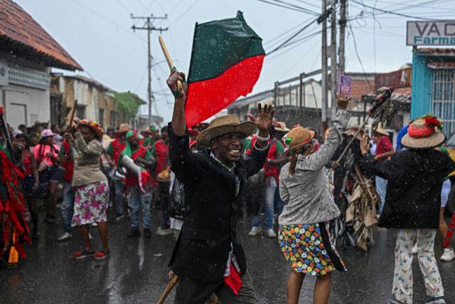 A man with a wooden machete pushes people aside during the celebration of Holy Innocents’ Day in Caucagua, Miranda state, Venezuela on December 28, 2025. (Photo by Federico PARRA / AFP)