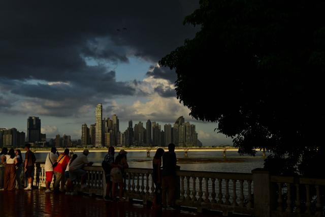 Tourists take pictures of the city skyline from Panama City's old town on December 28, 2025. (Photo by MARTIN BERNETTI / AFP)