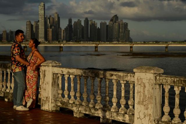A couple is seen with the skyline of the city in the background in Panama City on December 28, 2025. (Photo by MARTIN BERNETTI / AFP)