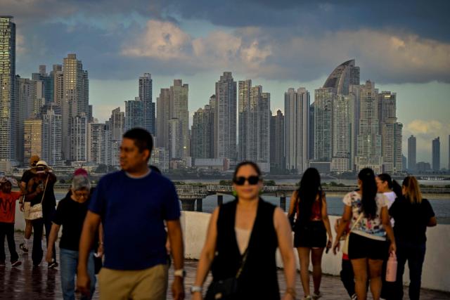 Tourists walk through the Casco Viejo historic district with the skyline of the city in the background in Panama City on December 28, 2025. (Photo by MARTIN BERNETTI / AFP)