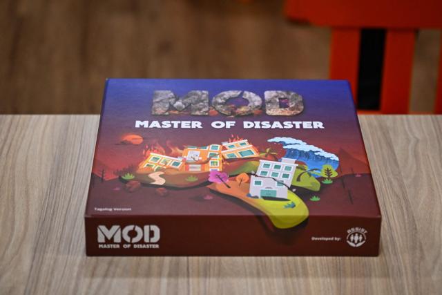 This photo taken on December 9, 2025, shows the Master of Disaster, a board game about disaster preparedness, at a library in Valenzuela, Metro Manila. In a library in the Philippines, a die rattles on the surface of a board before coming to a stop, putting one of its players directly in the path of a powerful typhoon. (Photo by Jam STA ROSA / AFP) / TO GO WITH STORY: Philippines-environment-disaster-climate-game, FOCUS by Pam CASTRO