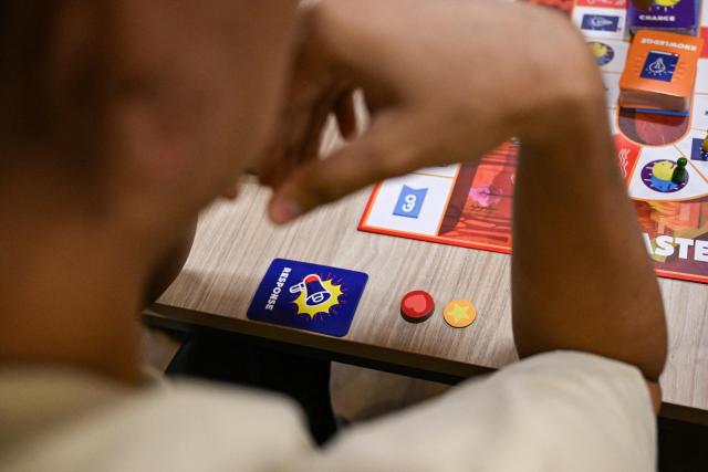 This photo taken on December 9, 2025, shows participants playing Master of Disaster, a board game about disaster preparedness, at a library in Valenzuela, Metro Manila. In a library in the Philippines, a die rattles on the surface of a board before coming to a stop, putting one of its players directly in the path of a powerful typhoon. (Photo by Jam STA ROSA / AFP) / TO GO WITH STORY: Philippines-environment-disaster-climate-game, FOCUS by Pam CASTRO