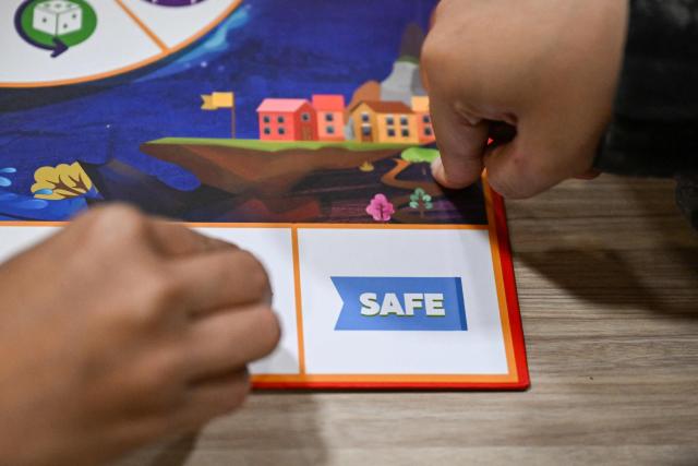 This photo taken on December 9, 2025, shows participants play Master of Disaster, a board game about disaster preparedness at a library in Valenzuela, Metro Manila. In a library in the Philippines, a die rattles on the surface of a board before coming to a stop, putting one of its players directly in the path of a powerful typhoon. (Photo by Jam STA ROSA / AFP) / TO GO WITH STORY: Philippines-environment-disaster-climate-game, FOCUS by Pam CASTRO