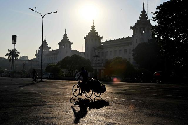 A trishaw driver transporting goods drives past Yangon train station in Yangon on December 29, 2025. (Photo by Nhac NGUYEN / AFP)