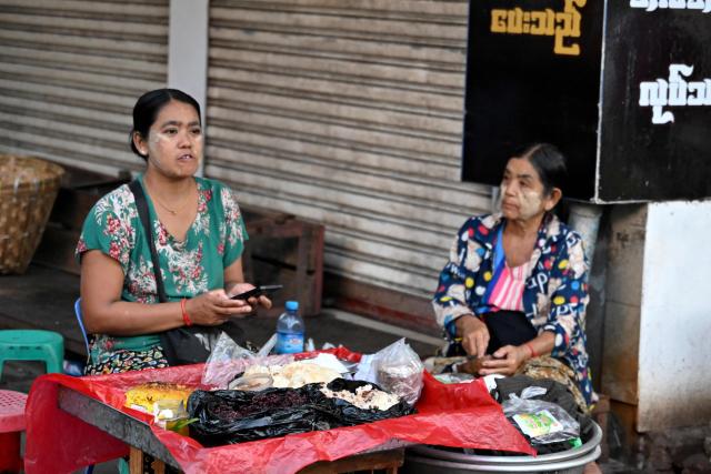 Sticky rice vendors sit and wait for customers in Yangon on December 29, 2025. (Photo by Nhac NGUYEN / AFP)