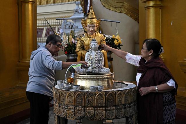 Devotees pour water over a statue of Buddha at Shwedagon Pagoda in Yangon on December 29, 2025. (Photo by Lillian SUWANRUMPHA / AFP)
