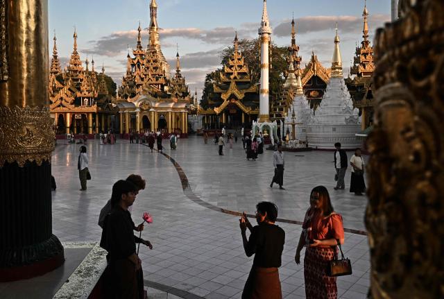 People take pictures at Shwedagon Pagoda in Yangon on December 29, 2025. (Photo by Lillian SUWANRUMPHA / AFP)