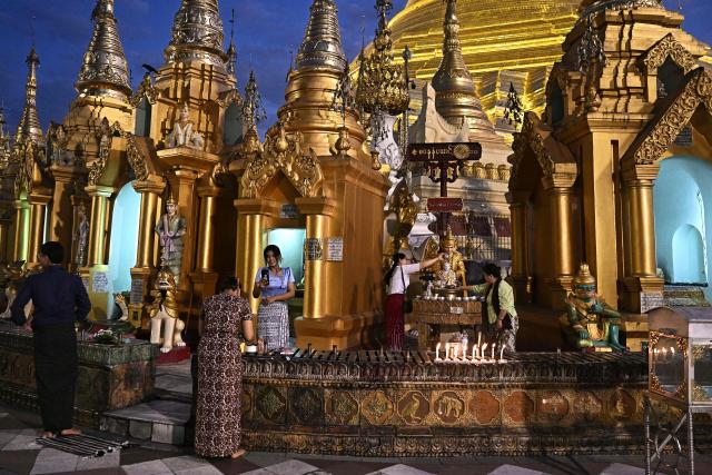 People pay their respects at Shwedagon Pagoda in Yangon on December 29, 2025. (Photo by Lillian SUWANRUMPHA / AFP)