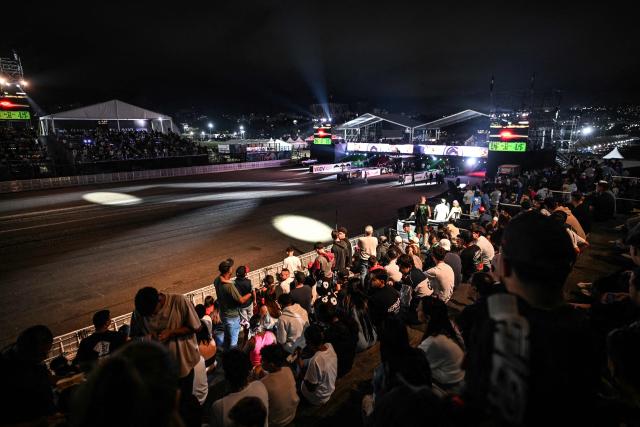 Attendees watch a car race during a car exhibition at La Carlota air base in Caracas on December 28, 2025. (Photo by Juan BARRETO / AFP)