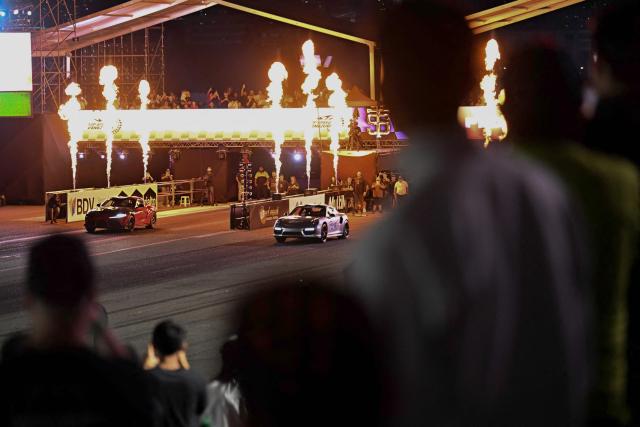 Attendees watch a car race during a car exhibition at La Carlota air base in Caracas on December 28, 2025. (Photo by Juan BARRETO / AFP)
