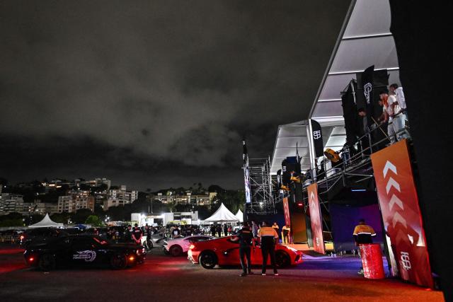Pilots prepare themselves with their cars to participate in a car exhibition at La Carlota air base in Caracas on December 28, 2025. (Photo by Juan BARRETO / AFP)