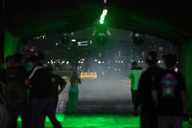 A pilot participate in a car exhibition at La Carlota air base in Caracas on December 28, 2025. (Photo by Juan BARRETO / AFP)