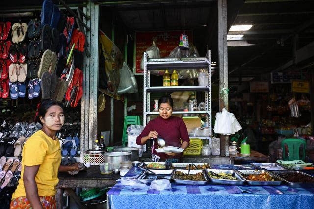 A vendor prepares a meal for a customer at a market in Naypyidaw on December 29, 2025, a day after the first phase of Myanmar's general election. (Photo by Sai Aung MAIN / AFP)