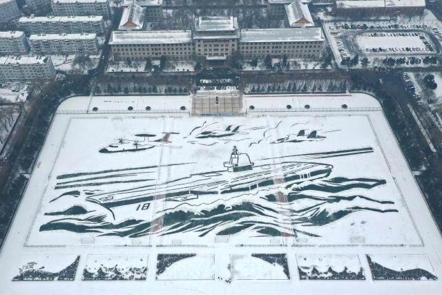This aerial picture taken on December 28, shows a pattern of warship modelled after the Fujian aircraft carrier “painted” onto the snow by staff and students at Harbin Engineer University in Harbin, China’s northeast Heilongjiang province. (Photo by AFP) / China OUT