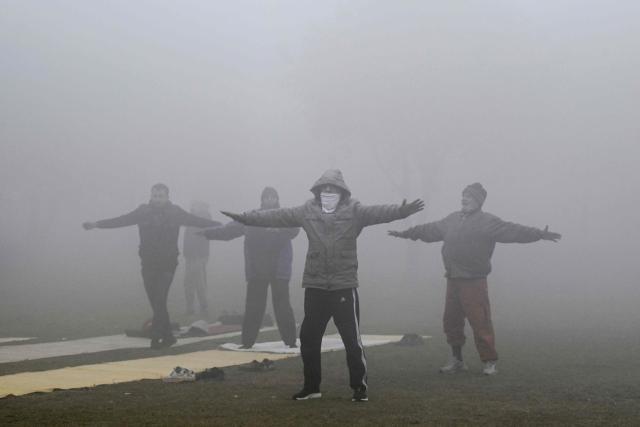 People exercise at a park as dense smog engulfs Lahore on December 29, 2025. (Photo by Arif ALI / AFP)