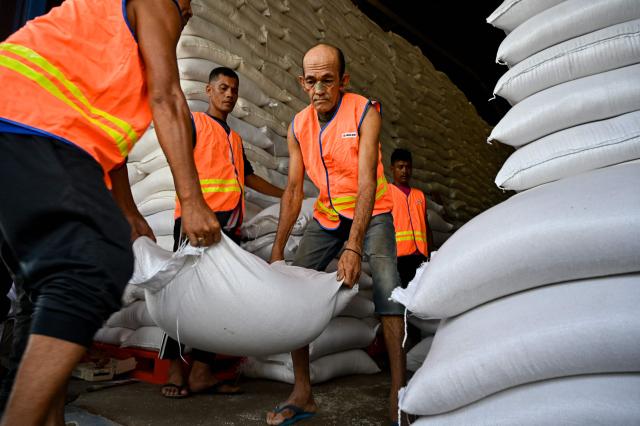 Workers unload sacks of rice at the Indonesian Logistics Bureau (BULOG) warehouse in Lambaro, Aceh province on December 29, 2025. (Photo by CHAIDEER MAHYUDDIN / AFP)
