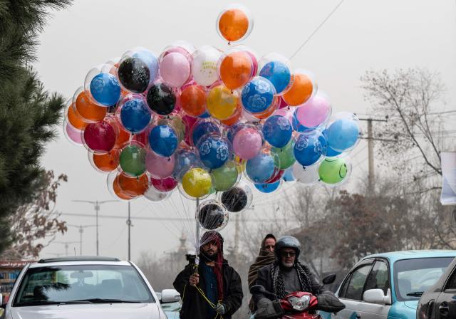 TOPSHOT - An Afghan balloon vendor wades through traffic as he looks for customers along a busy street in Kabul on December 29, 2025. (Photo by Wakil KOHSAR / AFP)
