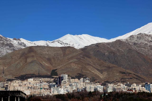 A photograph shows the Iranian capital Tehran with the snow-covered Alborz mountain range in the background on December 29, 2025. Tehran has seen intermittent rain since early December after months of dry weather, partially replenishing some of the city's reservoirs but leaving overall levels critically low. Iran, a largely arid country, has for years suffered chronic dry spells and heat waves, which are expected to worsen with climate change. (Photo by ATTA KENARE / AFP)