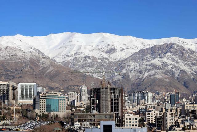 A photograph shows the Iranian capital Tehran with the snow-covered Alborz mountain range in the background on December 29, 2025. Tehran has seen intermittent rain since early December after months of dry weather, partially replenishing some of the city's reservoirs but leaving overall levels critically low. Iran, a largely arid country, has for years suffered chronic dry spells and heat waves, which are expected to worsen with climate change. (Photo by ATTA KENARE / AFP)