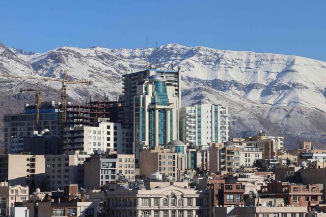 A photograph shows buildings in the Iranian capital Tehran with the snow-covered Alborz mountain range in the background on December 29, 2025. Tehran has seen intermittent rain since early December after months of dry weather, partially replenishing some of the city's reservoirs but leaving overall levels critically low. Iran, a largely arid country, has for years suffered chronic dry spells and heat waves, which are expected to worsen with climate change. (Photo by ATTA KENARE / AFP)