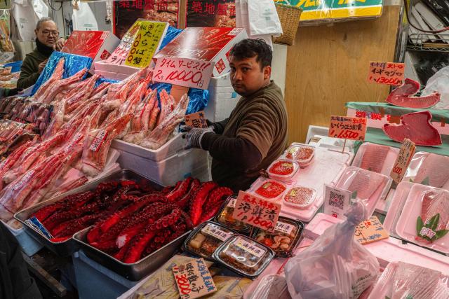 Vendors tend to their respective seafood stalls selling octopus tentacles and crab legs among other items ahead of the new year in Tokyo's Ueno shopping district on December 29, 2025. (Photo by Philip FONG / AFP)