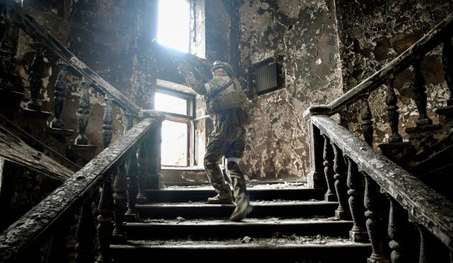 (FILES) A Russian soldier climbs stairs at the Mariupol drama theatre, hit on March 16 by an airstrike, on April 12, 2022 in Mariupol, as Russian troops intensify a campaign to take the strategic port city, part of an anticipated massive onslaught across eastern Ukraine, while Russia's President makes a defiant case for the war on Russia's neighbour. A theatre that became one of the bombed out symbols of a Russian siege of the city of Mariupol in eastern Ukraine in 2022 has reopened after a huge redevelopment, Russian authorities have announced. (Photo by Alexander NEMENOV / AFP)