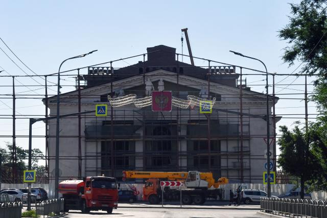 (FILES) Construction workers rebuild the Mariupol Drama Theatre in the Russian-controlled Azov Sea port city of Mariupol in southeastern Ukraine on July 15, 2025, amid the ongoing Russian-Ukrainian conflict. A theatre that became one of the bombed out symbols of a Russian siege of the city of Mariupol in eastern Ukraine in 2022 has reopened after a huge redevelopment, Russian authorities have announced. (Photo by Olga MALTSEVA / AFP)