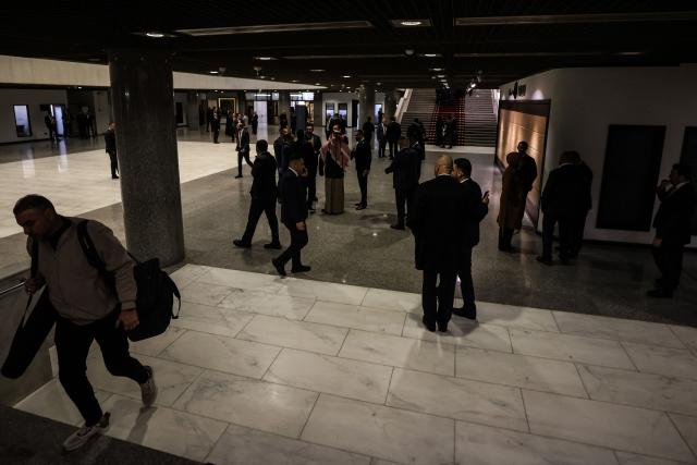 Journalists and officials walk through the hall of Iraq’s parliament building in Baghdad as newly elected lawmakers are due to hold their first session on December 29, 2025. (Photo by AHMAD AL-RUBAYE / AFP)