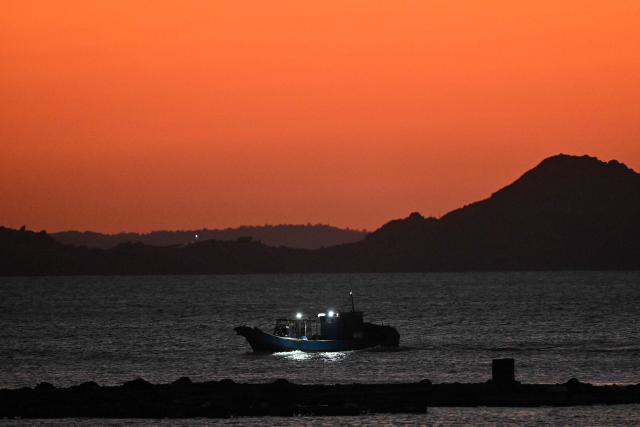 A fishing boat is seen from Pingtan island, the closest point to Taiwan, in eastern China’s Fujian province on December 29, 2025. China launched live-fire drills around Taiwan on December 29 that it said would simulate a blockade of the self-ruled island's key ports, prompting Taipei to condemn Beijing's "military intimidation". (Photo by ADEK BERRY / AFP)