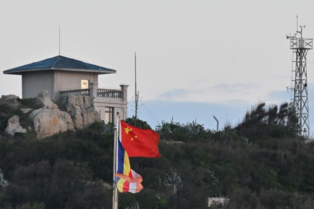 The Chinese flag (C) is seen on Pingtan island, the closest point to Taiwan, in eastern China’s Fujian province on December 29, 2025. China launched live-fire drills around Taiwan on December 29 that it said would simulate a blockade of the self-ruled island's key ports, prompting Taipei to condemn Beijing's "military intimidation". (Photo by ADEK BERRY / AFP)