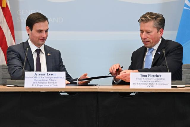 US Under Secretary of State for Foreign Assistance, Humanitarian Affairs and Religious Freedom Jeremy Lewin (L) and United Nations Under-Secretary-General for Humanitarian Affairs Tom Fletcher take part in the signing ceremony of a $2 billion pledge of United States for United Nations humanitarian aid in 2026, at the US Mission in Geneva, on December 29, 2025. According to UN data, the United States remains the top humanitarian aid donor in the world, but that amount fell significantly in 2025 to $2.7 billion, down from around $11 billion in 2023 and 2024 and from over $14 billion in 2022. (Photo by Fabrice COFFRINI / AFP)
