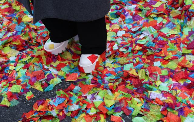 People stand in rain soaked confetti in Times Square during New Year’s Eve rehearsals as part of the Planet Fitness test air worthiness of confetti in New York on December 29, 2025. (Photo by TIMOTHY A. CLARY / AFP)