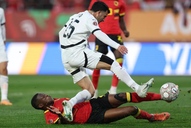 Egypt's midfielder #25 Zizo (C) fights for the ball with Angola's defender #02 Nurio Fortuna (L) during the Africa Cup of Nations (CAN) Group B football match between Angola and Egypt at Adrar Stadium in Agadir on December 29, 2025. (Photo by FRANCK FIFE / AFP)