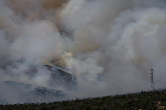 This aerial view shows a helicopter fighting a forest fire in San Carlos de Apoquindo in Santiago on December 29, 2025. (Photo by Javier TORRES / AFP)