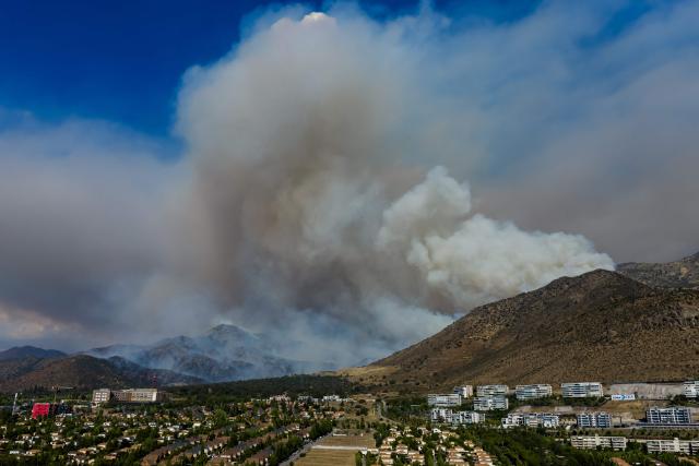 This aerial view shows a forest fire in San Carlos de Apoquindo in Santiago on December 29, 2025. (Photo by Javier TORRES / AFP)