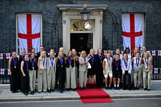 (FILES) England's Dutch head coach Sarina Wiegman (CL) stands with Captain England's defender #06 Leah Williamson (CR) stand at the centre of the England Women's national football team with the European Championship trophy as they pose upon arriving for a reception at 10 Downing Street in central London on July 28, 2025. England's "Lionesses" featured heavily in the 2026 New Years Honours List after their Euros win in the summer. Captain Leah Williamson was made a Commander of the Order of the British Empire (CBE), Alex Greenwood, Keira Walsh, Georgia Stanway and Ella Toone, were each made a Member of the Order of the British Empire (MBE) and the team's Dutch manager Sarina Wiegman was awarded an honorary damehood. (Photo by Ben STANSALL / AFP)
